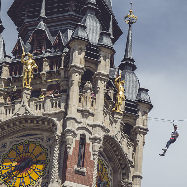 personne en tyrolienne passant devant le Beffroi de Calais