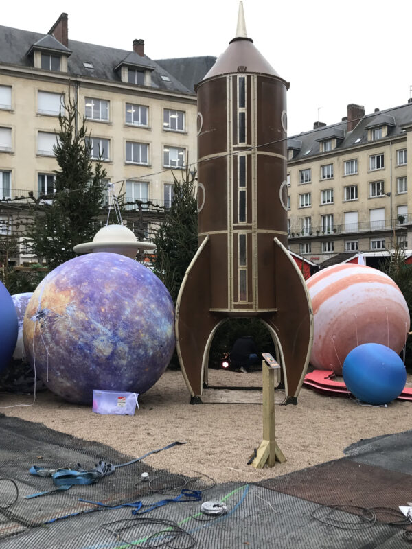 scénographie en centre ville avec une fusée et des planètes